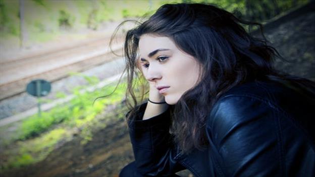 Girl standing on bridge leaning on her hand